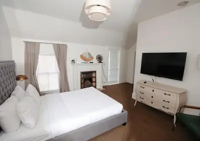 a white bedroom with a bed and a tv at Norment Parry by The Wellborn in Orlando