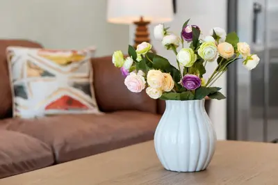 a white vase with a bouquet of flowers on a table at New 5BR Villa Near Disney I Resort Lazy River in Orlando