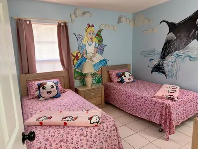 a childs bedroom with two beds and a disney princess mural at Magic getaway in Kissimmee
