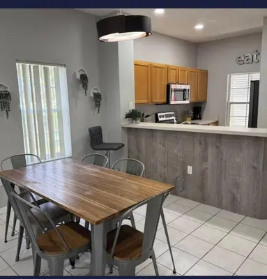 a kitchen with a wooden table and some chairs at TownHouse at Emerald Island Resort Near Disney in Kissimmee