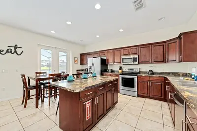 a large kitchen with wooden cabinets and a dining room at Family Retreat at Lake Berkley Resort! in Kissimmee