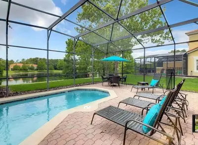 a swimming pool with chairs and an umbrella at Condomínio Encantada c/ Piscina & Vista ao Lago in Kissimmee