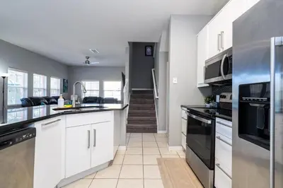 a kitchen with white cabinets and appliances and a hallway at Condomínio Encantada c/ Piscina & Vista ao Lago in Kissimmee