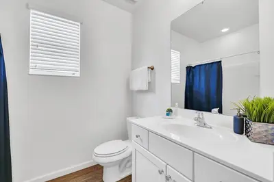a white bathroom with a toilet and a sink at Lakefront | Sleeps 18 | 8-Bed Villa w/ Pool & Epic in Kissimmee