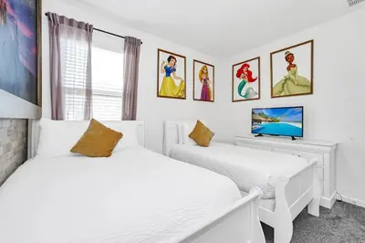 two beds in a white room with paintings on the wall at Lakefront | Sleeps 18 | 8-Bed Villa w/ Pool & Epic in Kissimmee