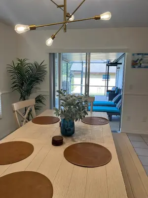 a dining room table with a vase of flowers on it at Dream Getaway Nr Disney! Own Pool & Modern Feel! in Orlando