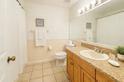 a bathroom with a sink and a toilet and a mirror at Casa 3Q c/ Piscina — 10 min da Disney in Kissimmee