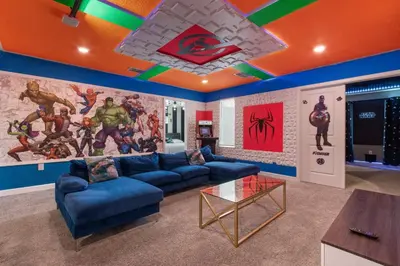 a living room with blue couches and a marvel mural at Close to Disney! Pool/Spa/Game & Movie room! in Kissimmee