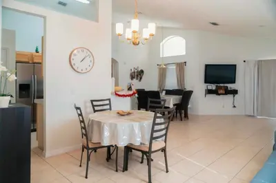 a dining room and living room with a table and chairs at Gated Pool Home 20 Min to Disney, Uni, MCO in Kissimmee