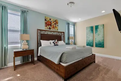 a bedroom with a large bed and a table and windows at 480 Lasso Dr. · 480 Villa - Large Luxury 7BD Home - SpaPool in Orlando