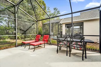 a patio with red chairs and a table with a glassconservatory at 213 Hideaway Beach way in Kissimmee