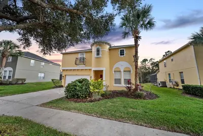 a yellow house with a palm tree in a yard at Cozy Villa 08 BedroomsPoolGame Room in Kissimmee