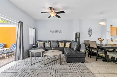 a living room with a black leather couch and a table at Family Escape! HotTub+Grill+Disney! in Kissimmee