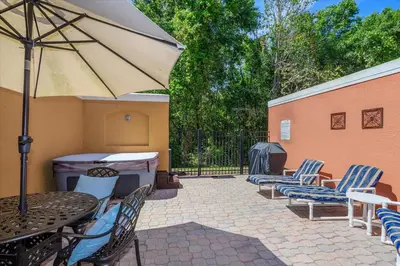 a patio with chairs and a table and an umbrella at Hot Tub, BBQ - Near Disney Fun! in Kissimmee