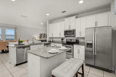 a kitchen with white cabinets and stainless steel appliances at Private Heated Pool Game room 6MI to Disney in Orlando