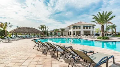 a swimming pool with chairs and a building at Your Beautiful Hideaway 9-Bedroom Luxury Villa in Kissimmee