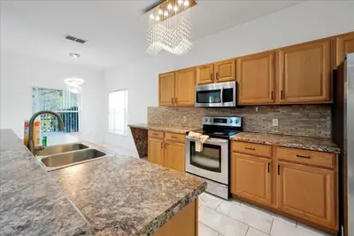 a kitchen with wooden cabinets and stainless steel appliances at Famous 5 Star Home in Kissimmee with Game Room in Kissimmee