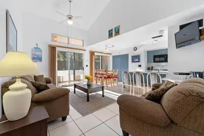 a living room with two couches and a kitchen at Mango Keys Getaway Near Theme Parks in Kissimmee