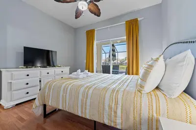a bedroom with a bed with a television and a dresser at Water View Pool Home Near Disney in Kissimmee