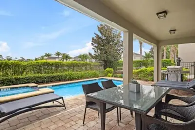 a patio with a table and chairs next to a swimming pool at 381 Fantastic Home Near Disney 5BD 5BT 14P in Orlando