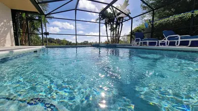 a large swimming pool with blue chairs in it at 20 mins Disney, Private Heated Pool & Spa, Games Room, Spacious, Good for Groups in Orlando
