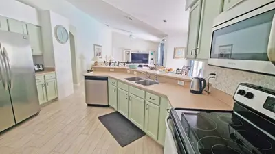 a large kitchen with green cabinets and stainless steel appliances at 20 mins Disney, Private Heated Pool & Spa, Games Room, Spacious, Good for Groups in Orlando