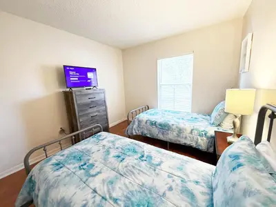 a bedroom with two beds and a tv on the wall at The Family Den in Kissimmee
