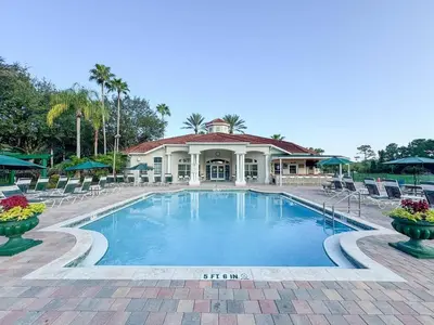 a swimming pool with chairs and a building at The Family Den in Kissimmee