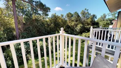 a white railing on a porch with trees in the background at Magari at Emerald Island in Kissimmee