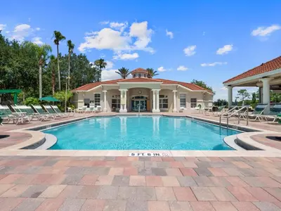 a swimming pool with chairs and a building at Floridian at Emerald Island in Kissimmee
