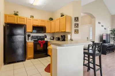 a kitchen with yellow cabinets and a black refrigerator at The Beauty at Emerald Island in Kissimmee