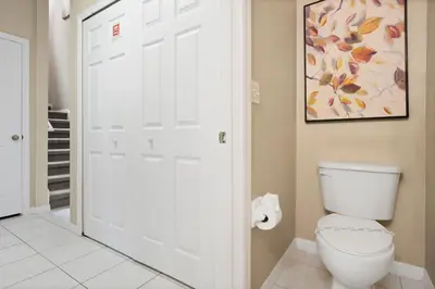 a bathroom with a toilet and a painting on the wall at The Beauty at Emerald Island in Kissimmee