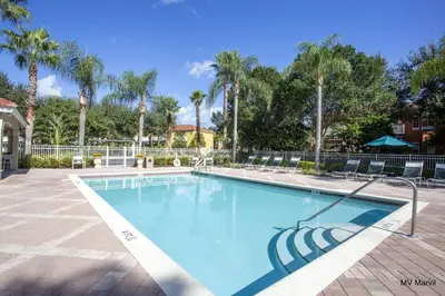 a large swimming pool with palm trees in a resort at Bella Vista at Emerald Island in Kissimmee