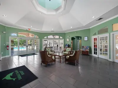 a living room with a table and chairs and green walls at Meriggiare at Emerald Island in Kissimmee
