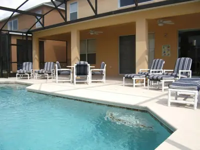 a group of chairs and a table next to a pool at La Isla at Paradise by PropertyChekker! in Kissimmee