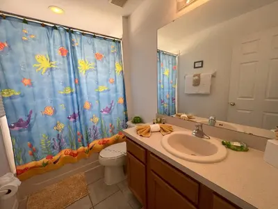 a bathroom with a sink and a shower curtain at La Isla at Paradise by PropertyChekker! in Kissimmee