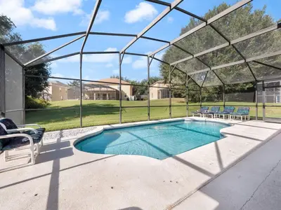 a swimming pool with a pergola and chairs around it at Oasis Key Retreat by PropertyChekker! in Kissimmee