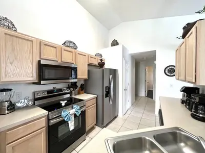 a kitchen with wooden cabinets and a stainless steel refrigerator at Oasis Key Retreat by PropertyChekker! in Kissimmee