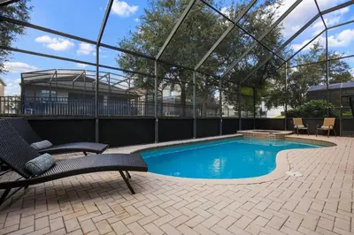 a swimming pool with two chairs next to a building at Mickey's Castle by PropertyChekker! in Orlando