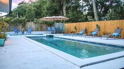 a swimming pool with chairs and an umbrella at Orlando Villa: Pool Garage & Garden View in Orlando