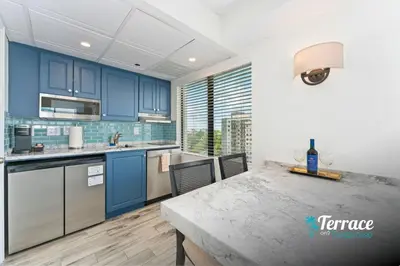 a kitchen with blue cabinets and a table at Fireworks View Studio Condo with Terrace and Kitchenette in Orlando