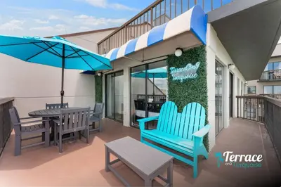 a patio with chairs and a table and an umbrella at Fireworks View Studio Condo with Terrace and Kitchenette in Orlando