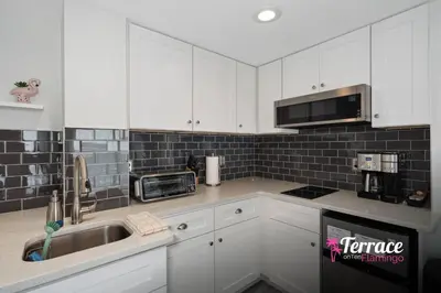 a kitchen with white cabinets and a sink at Gorgeous 2 Bed 2 Bath Flamingo Penthouse Volcano Bay View in Orlando