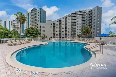 a swimming pool with chairs and buildings in the background at Relaxing 2 Bed 2 Bath Condo with Garden View Balcony 7 Min to Universal in Orlando