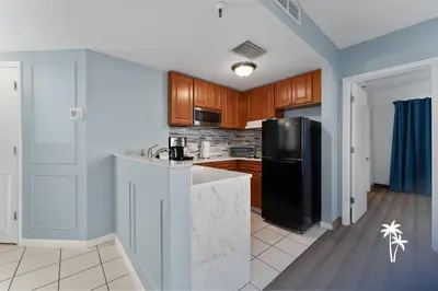 a kitchen with a black refrigerator and wooden cabinets at Relaxing 2 Bed 2 Bath Condo with Garden View Balcony 7 Min to Universal in Orlando