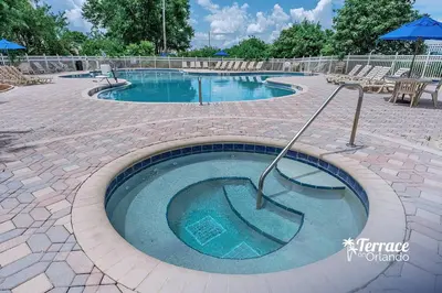 a large swimming pool with chairs and an umbrella at Superior Central Condo with Balcony 7 Min to Universal in Orlando