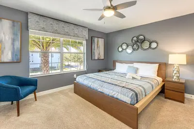 a bedroom with a bed and a blue chair at Lanai and Private Pool, 8 Mi to WDW Family Getaway! in Kissimmee