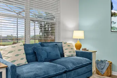 a blue couch in a living room with a window at 6 BR Home, Themed Rooms, Private Pool, Windsor Hills by Blue Sky Villas in Orlando