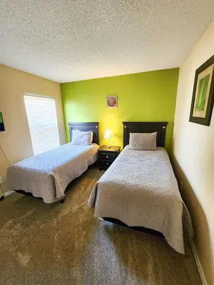 two beds in a room with green walls at Spacious 7BR Retreat w Pool & Jacuzzi V#202 in Kissimmee