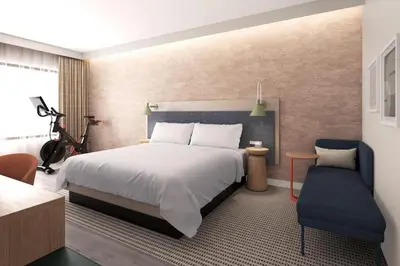 a bedroom with a large bed and a blue chair at EVEN Hotel Orlando Universal Blvd by IHG in Orlando